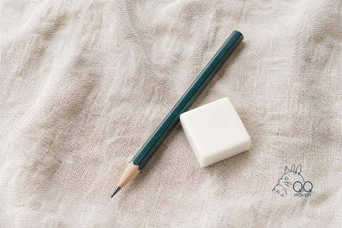 本色亚麻布上一支削尖的墨绿色木铅笔与一块方形白橡皮